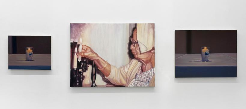 Three paintings on a gallery wall depicting candles with the one in the middle a person lighting one.