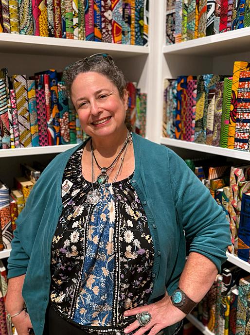 A woman smiling for a portrait in a colorful gallery.