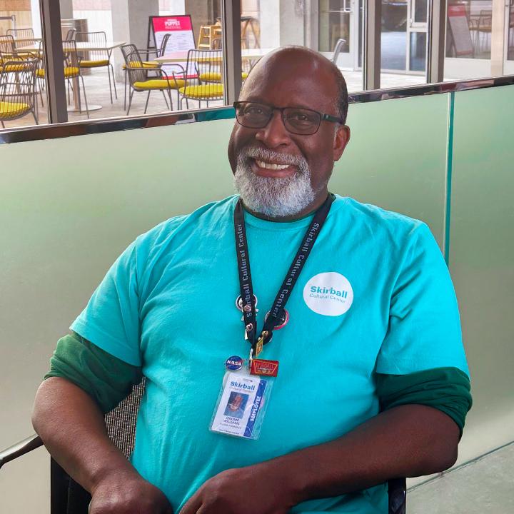 A man smiling behind the visitor service desk at the Skirball.