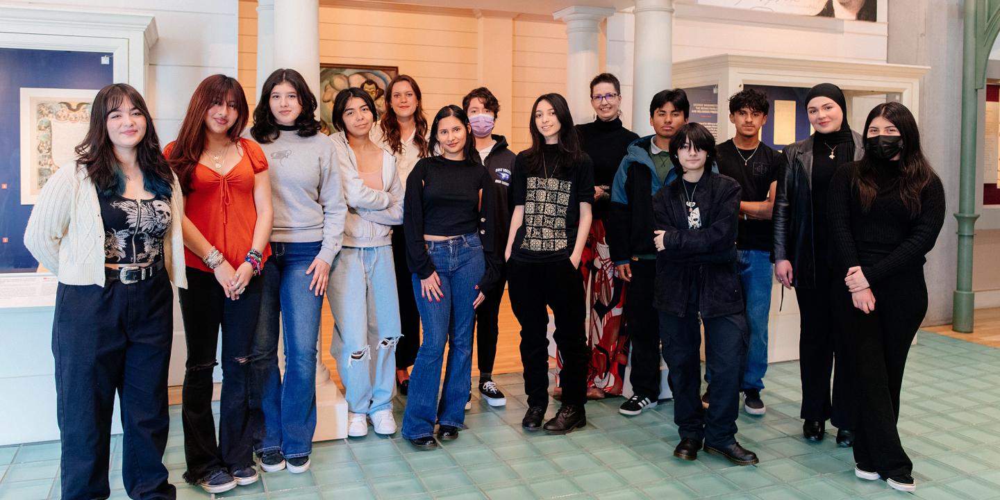 A group of teenagers posing in a group inside a gallery.
