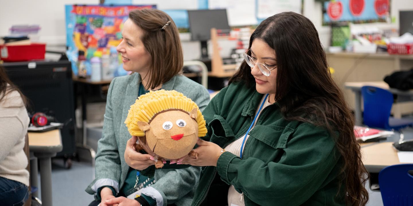 A teacher holds up an animal made of different materials in a classroom