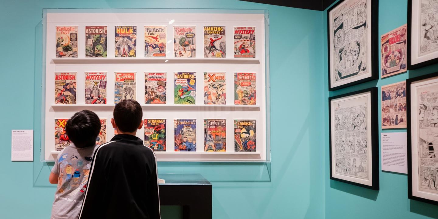 Two people view the exhibition Jack Kirby: Heroes and Humanity.