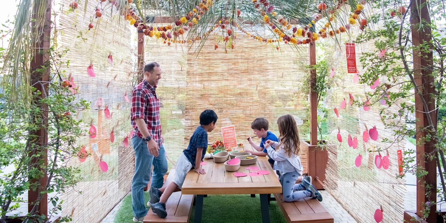 A family gathered under a sukkah made from natural materials.