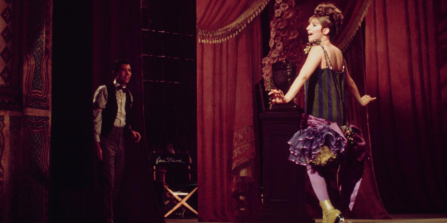 A woman sings on stage in a fancy short dress and roller-skates