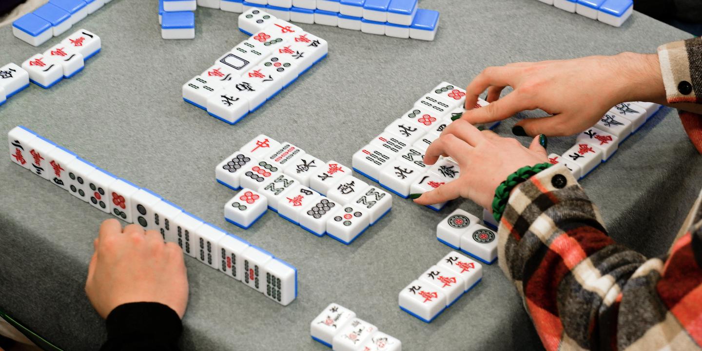 A table set up with colorful tiles and people playing Mahjong.