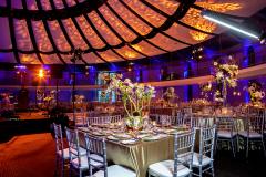 A gold table setting in a ballroom with elegant lighting and a dome-like ceiling.