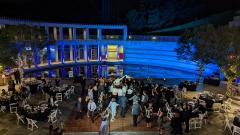 People dancing in an outdoor courtyard with a lily pond decorated with lights, tables, and a dance floor.