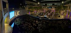An outdoor courtyard with a lily pond decorated with lights, tables, and a large projected screen.