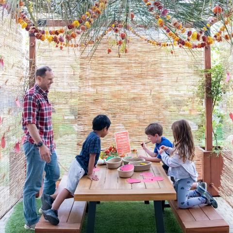 A family gathered under a sukkah made from natural materials.
