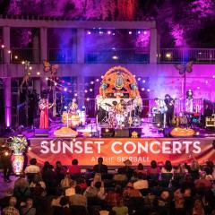 Image of outdoor stage with band playing and audience seated and listening. A large banner on the stage reads Skirball Stages