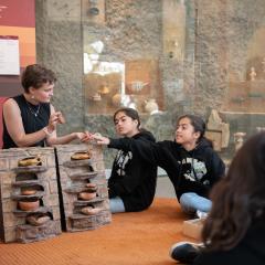 A student touches ancient artifacts.