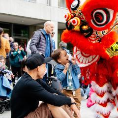A child stares excitedly at a red dragon puppet in the courtyard.