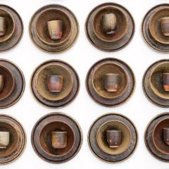 A set of plates, bowls, and cups made from pottery set up in a row.