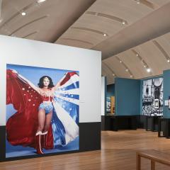 A wide gallery shot with a large mural of Wonder Woman and another with Superman.